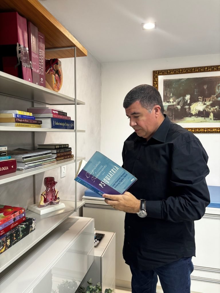 Dr. Kiffer Alves Moraes consultando literatura médica no consultório